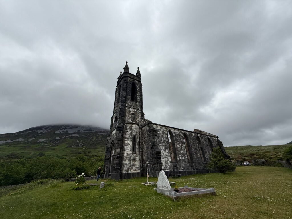 A historic Irish stone church beneath a heavy, cloudy sky